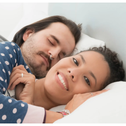 Femme souriante au lit avec son mari qui dort